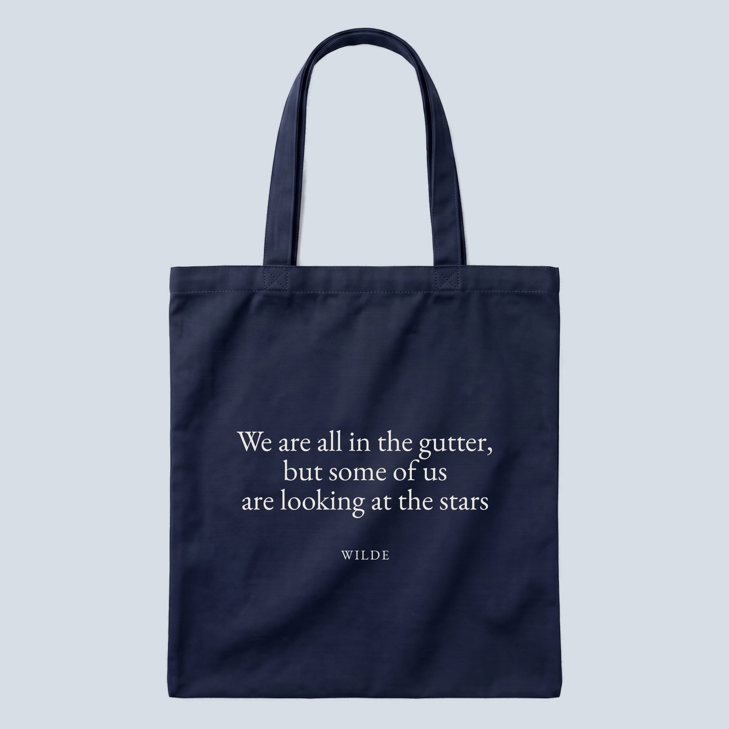 Wilde (Stars) quote tote bag by Subtext – cream text on a navy canvas tote with zip closure, front view.